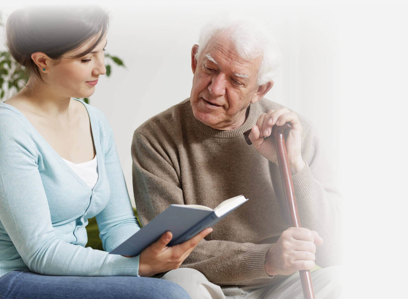 Caregiver helping a senior man read at home